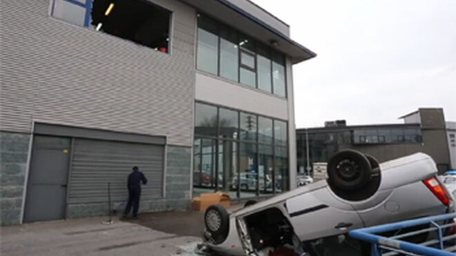 Un mecánico cae con un coche desde la planta alta de un taller